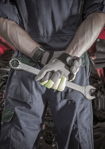 Mechanic in work gloves holding a large wrench behind their back.